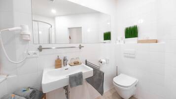 A modern bathroom with a white sink, mirror, and toilet.
