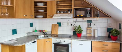 A compact kitchen with wooden cabinets, a built-in microwave, and a dishwasher.