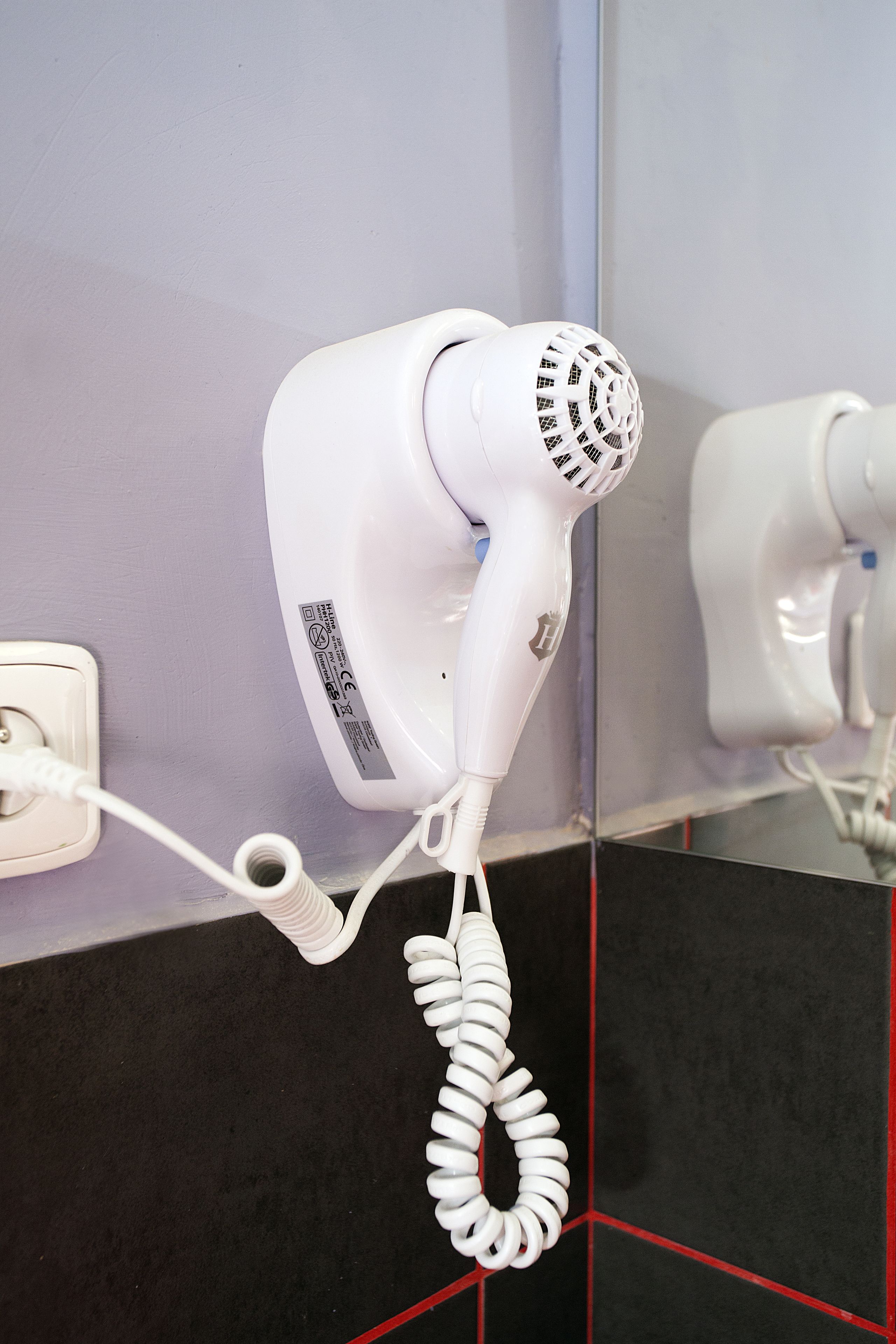 Un secador de pelo montado en la pared con un cable enrollado.