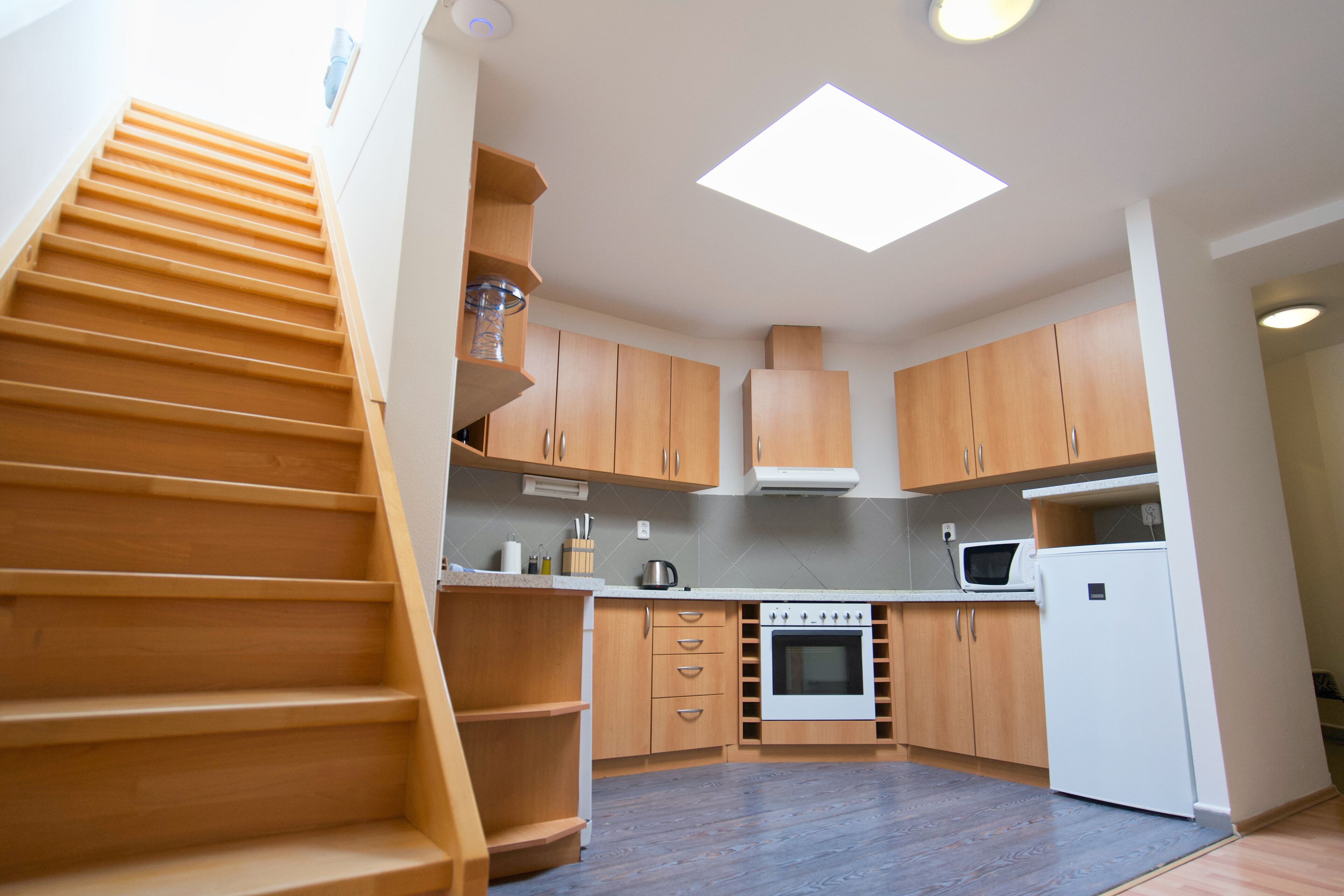 A kitchen with wooden cabinets, a stove, a microwave, and a refrigerator.