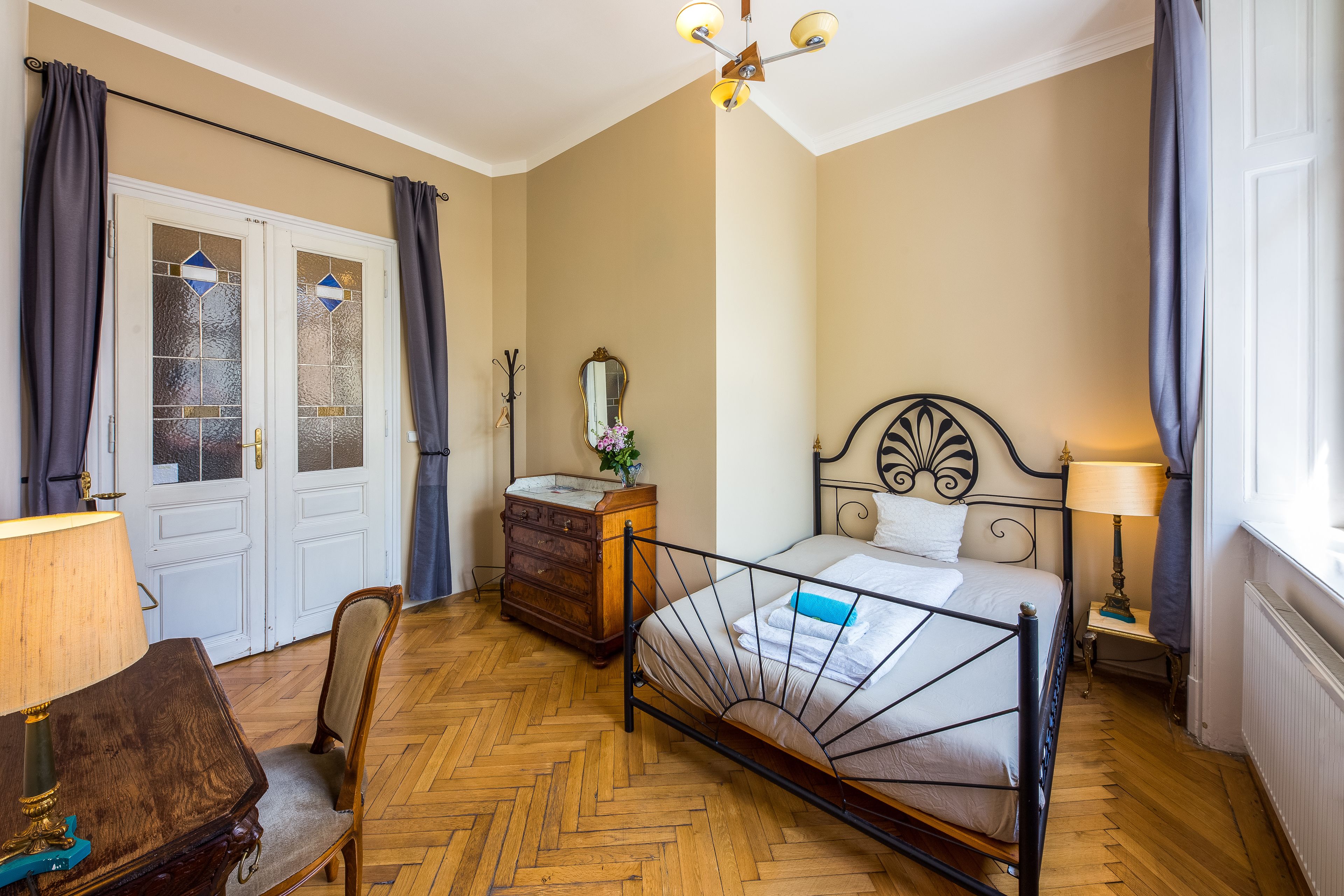 Un dormitorio con cama, cómoda, silla y una mesita de noche con lámpara.