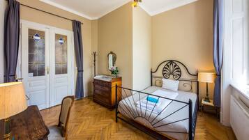 Un dormitorio con cama, cómoda, silla y una mesita de noche con lámpara.