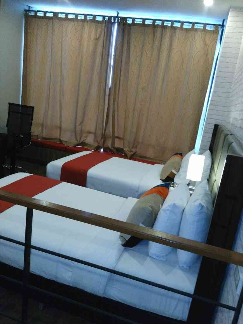 A hotel room with two beds, a desk, and a chair.
