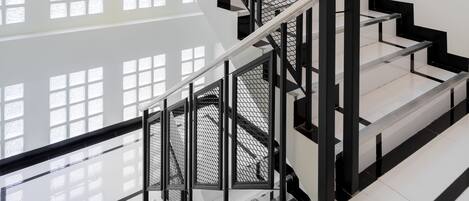 A modern staircase with black railings and white steps, leading to an upper floor with large windows.
