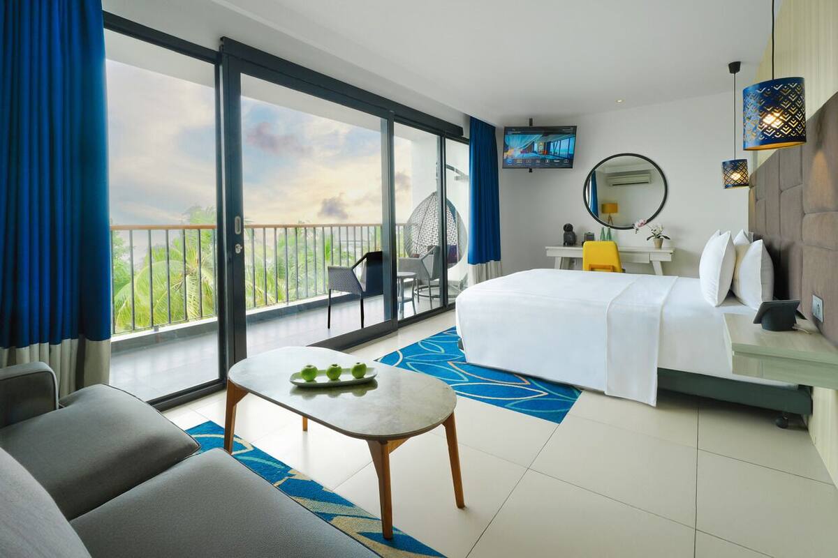 Une chambre d’hôtel avec un grand lit, un bureau, une chaise, une télévision et un balcon avec vue.