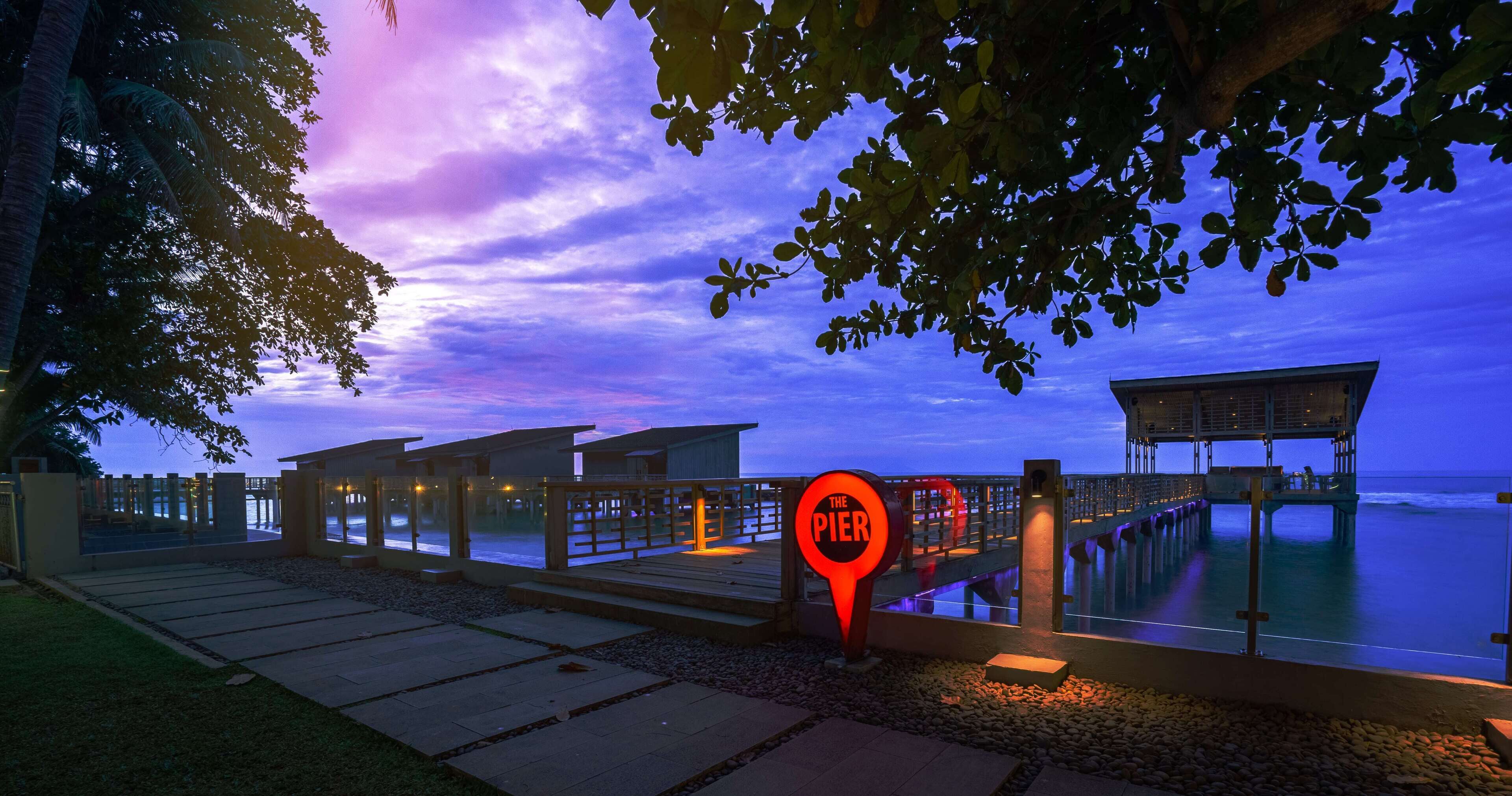 Un muelle con un cartel que dice "The Pier" al anochecer.