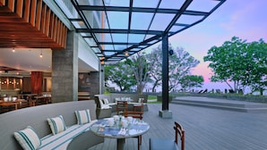 Un espace extérieur aménagé avec une table ronde, des sièges confortables et une vue sur les arbres et le ciel.