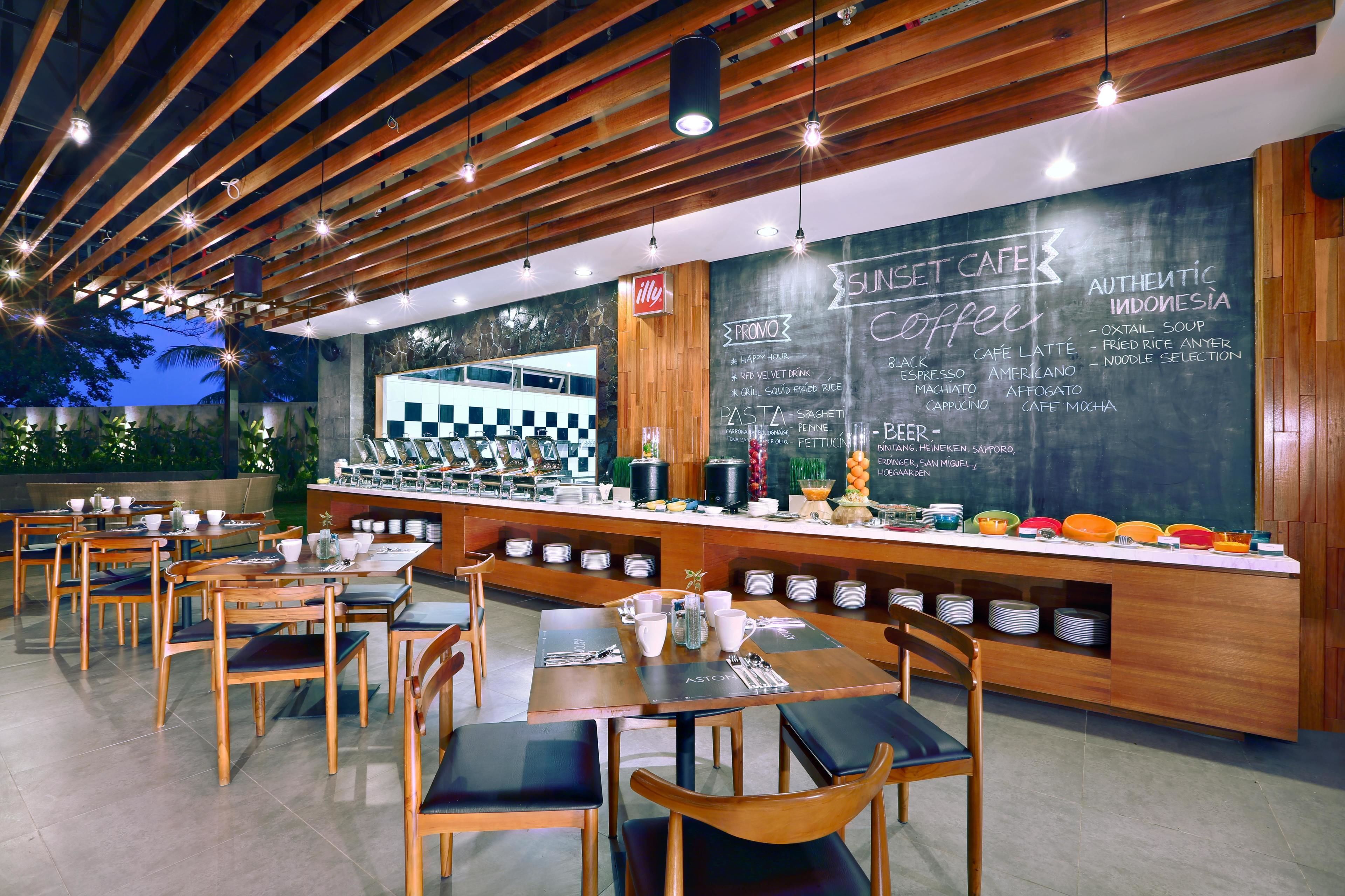 An outdoor cafe with wooden tables and chairs, a chalkboard menu, and a bar area.