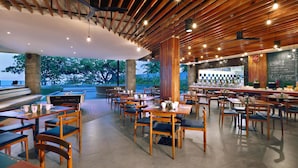Un restaurant avec des tables et des chaises en bois, un coin bar et une vue sur l’extérieur.