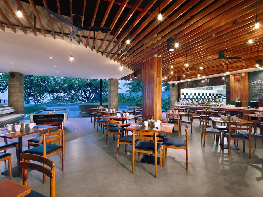 A restaurant with wooden tables and chairs, a bar area, and a view of the outdoors.