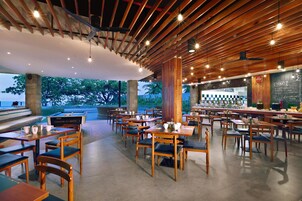 Un restaurante con mesas y sillas de madera, una zona de bar y vistas al exterior.