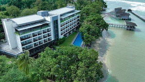 Un hôtel moderne doté d’une piscine, offrant une vue sur la plage et proposant des bungalows sur pilotis.