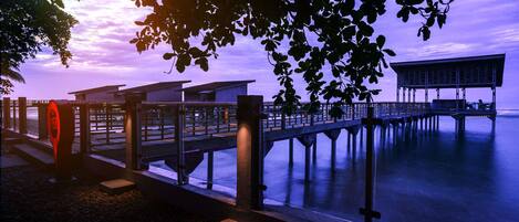 A pier extending into calm water with a modern building at the end.