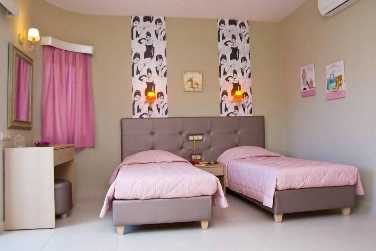 Ein Schlafzimmer mit zwei Betten, einem Nachttisch, einem Schminktisch und einem Spiegel.