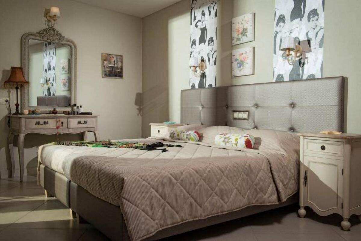 Ein Schlafzimmer mit einem großen Bett, einem Schminktischchen, einem Frisiertisch und einem Spiegel.