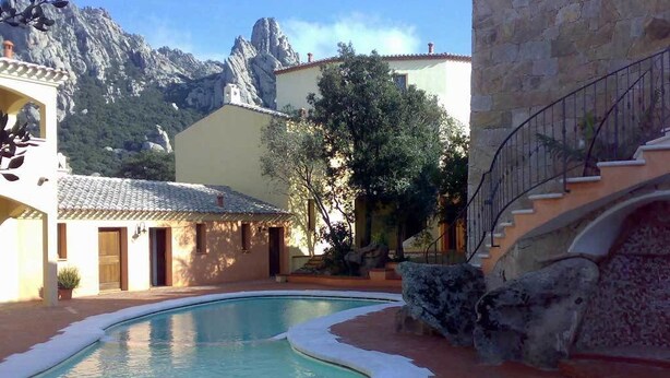A pool area with a stone wall, a staircase, and a mountain backdrop.