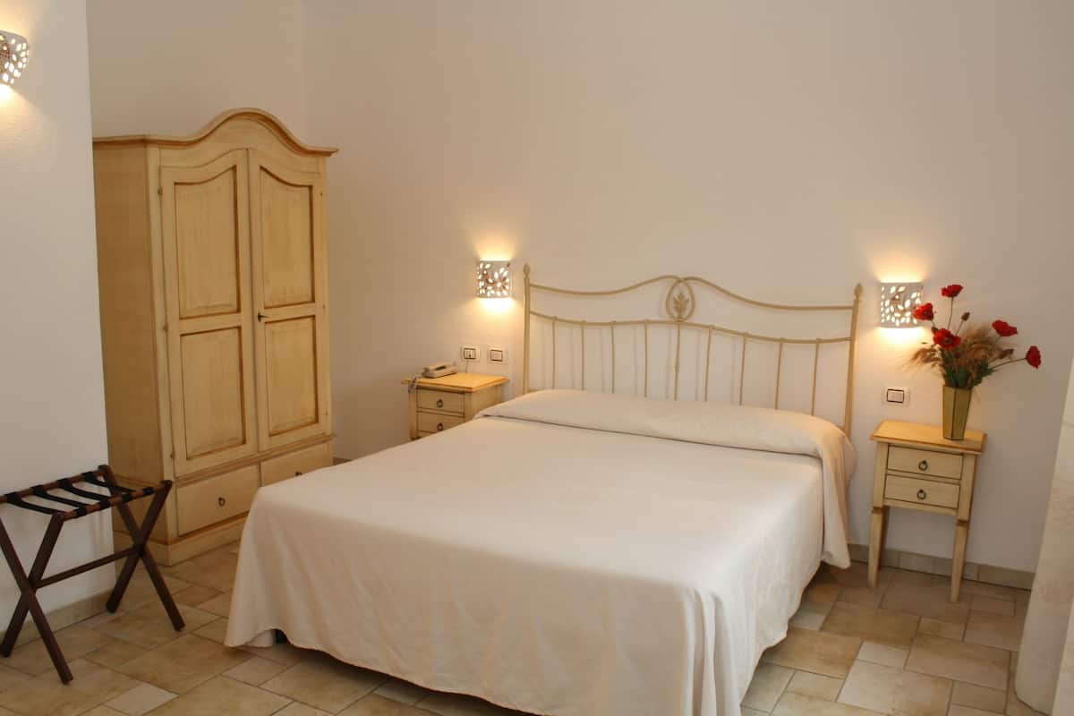 A bedroom with a bed, nightstands, a wardrobe, and a small table with a lamp.