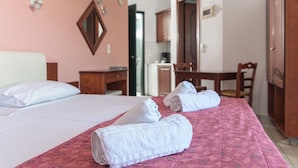 Une chambre d’hôtel avec deux lits, un bureau, une chaise et une kitchenette.