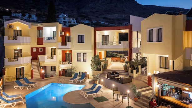 Un hôtel à étages, doté d’une piscine extérieure, de chaises longues et d’un bar.