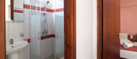 A bathroom with a glass-enclosed shower, a sink, and a toilet.