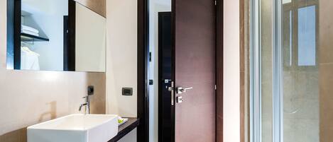 Un baño moderno con un espejo grande, un lavabo blanco y una zona de ducha.