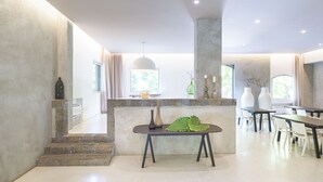 A modern dining area with a central island, a staircase leading to another level, and a view of the outdoors. - Ramo d'Aria Etna Boutique Hotel (Giarre)