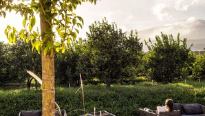 An outdoor seating area with chairs and tables, surrounded by greenery and a view of distant mountains. - Ramo d'Aria Etna Boutique Hotel (Giarre)