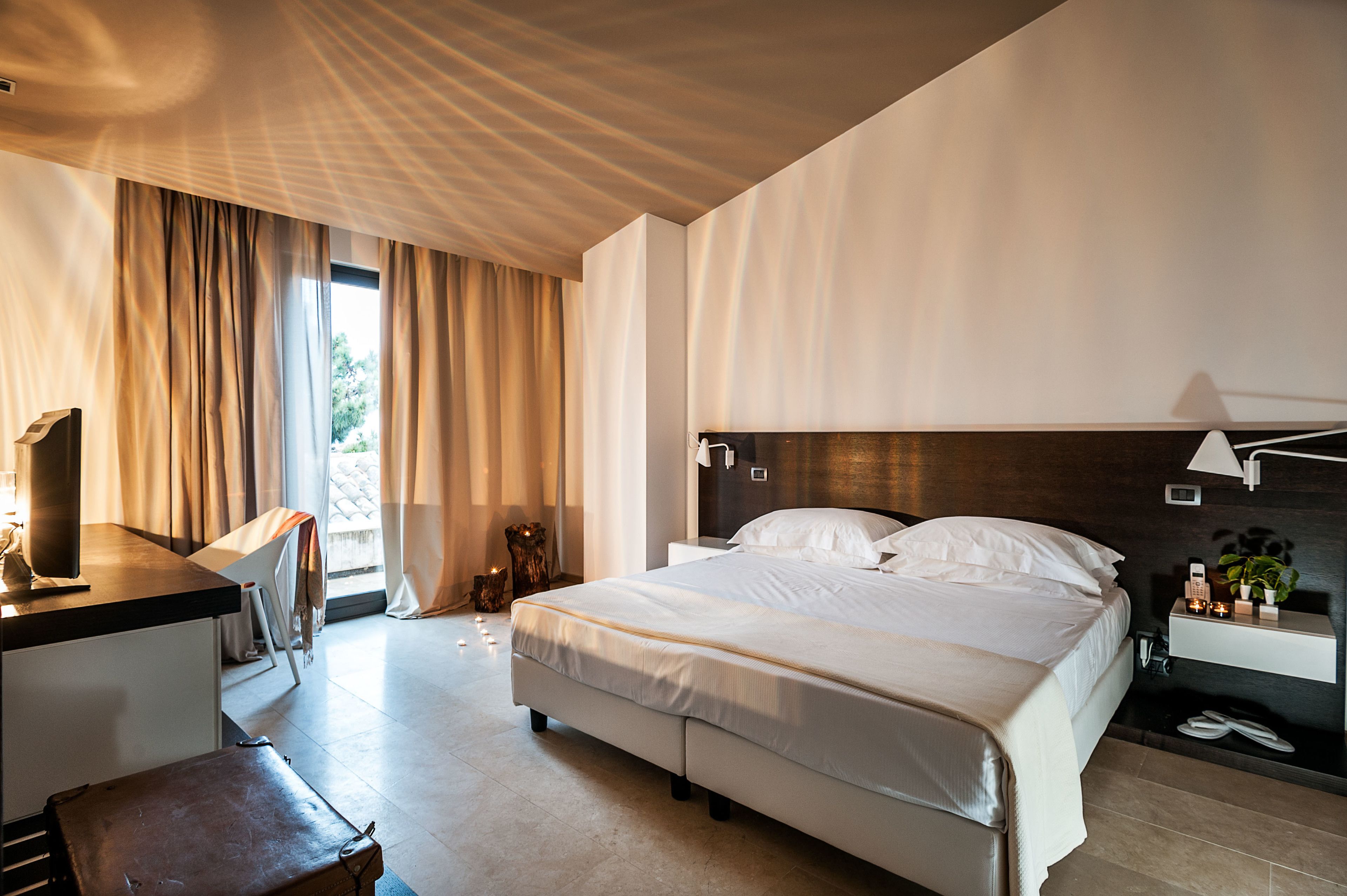 Una habitación de hotel moderna con una cama grande, un escritorio y una mesita de noche.
