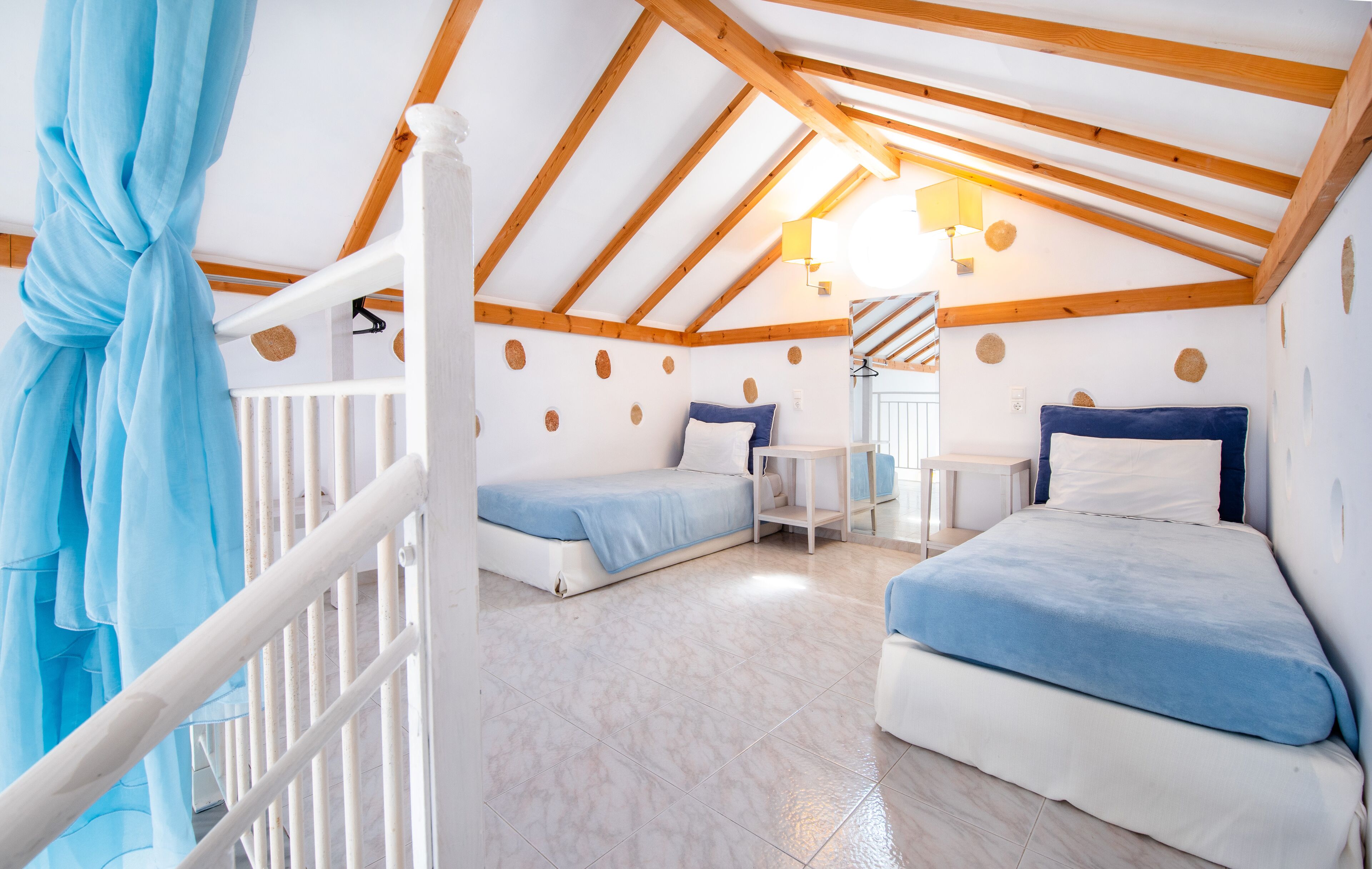 Una camera da letto mansardata accogliente con due letti, un tavolino e una scala.
