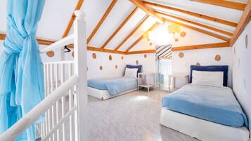 A cozy attic bedroom with two beds, a small table, and a staircase.