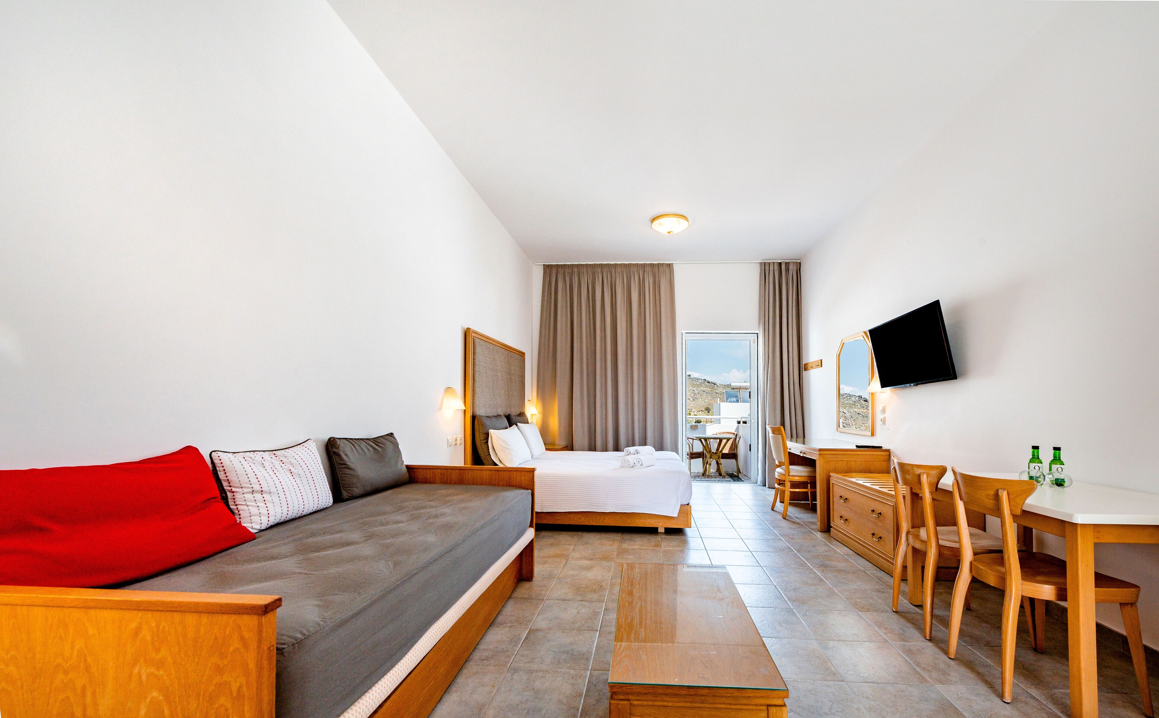 A hotel room with a bed, a sofa, a desk, and a TV.