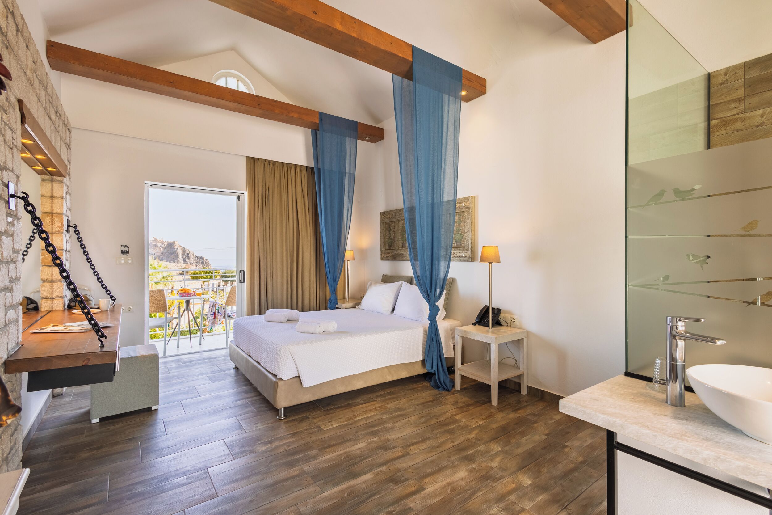 Una habitación de hotel moderna con cama, mesita de noche y baño con lavamanos y espejo.