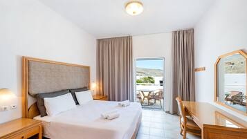 Una camera d'hotel con un letto, comodini, una scrivania e vista sull'esterno.