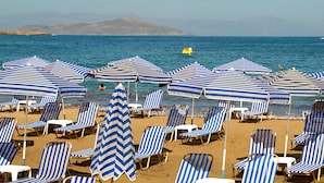 A beach with striped umbrellas and lounge chairs. - Klinakis Beach Hotel (Chania)