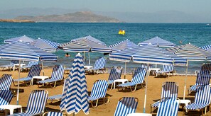 En la playa, sillas reclinables de playa, sombrillas, toallas de playa
