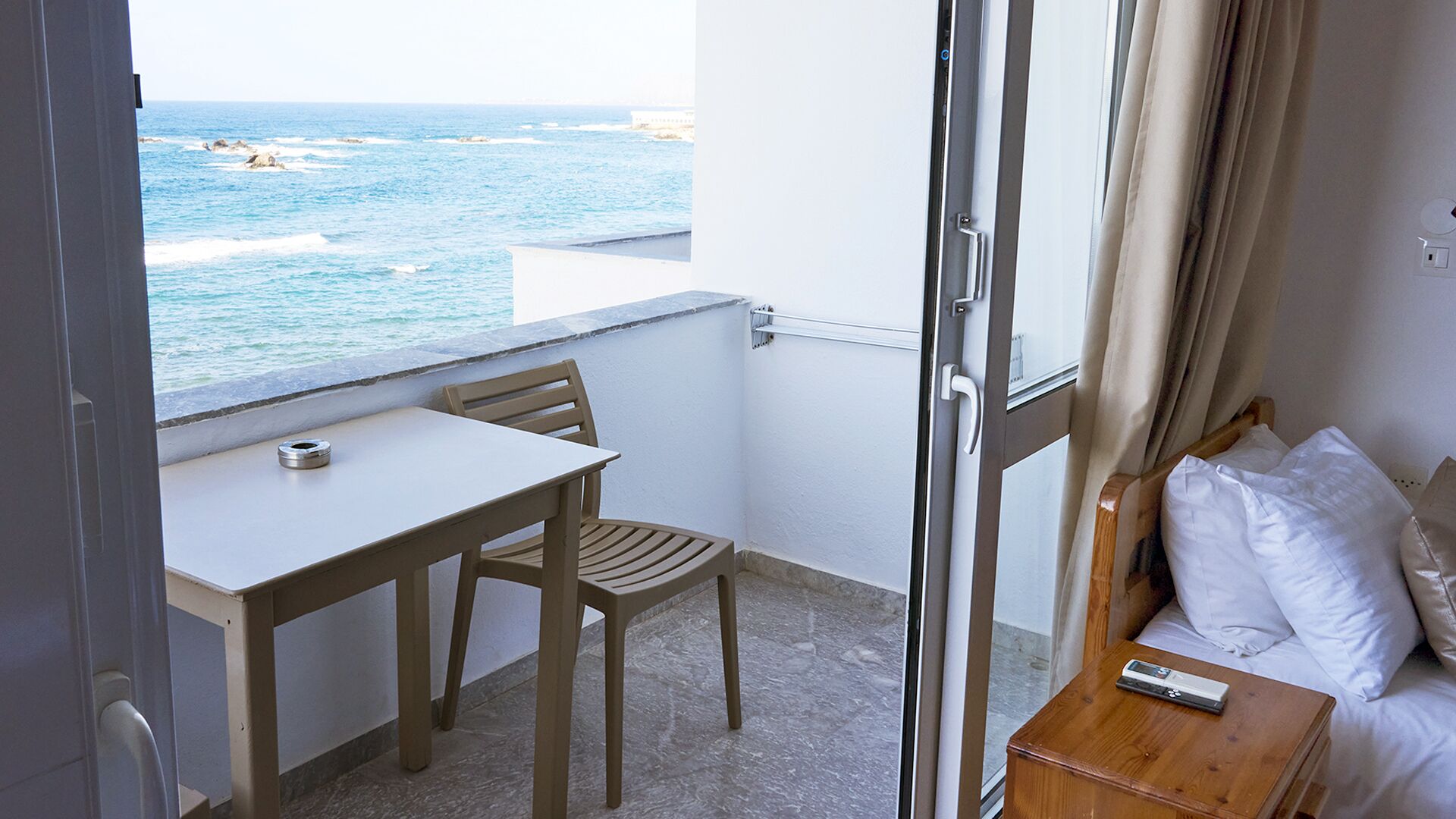 A balcony with a table and chair, a sofa, and a view of the sea.