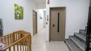 Un pasillo con una cuna de madera, una puerta y una escalera.