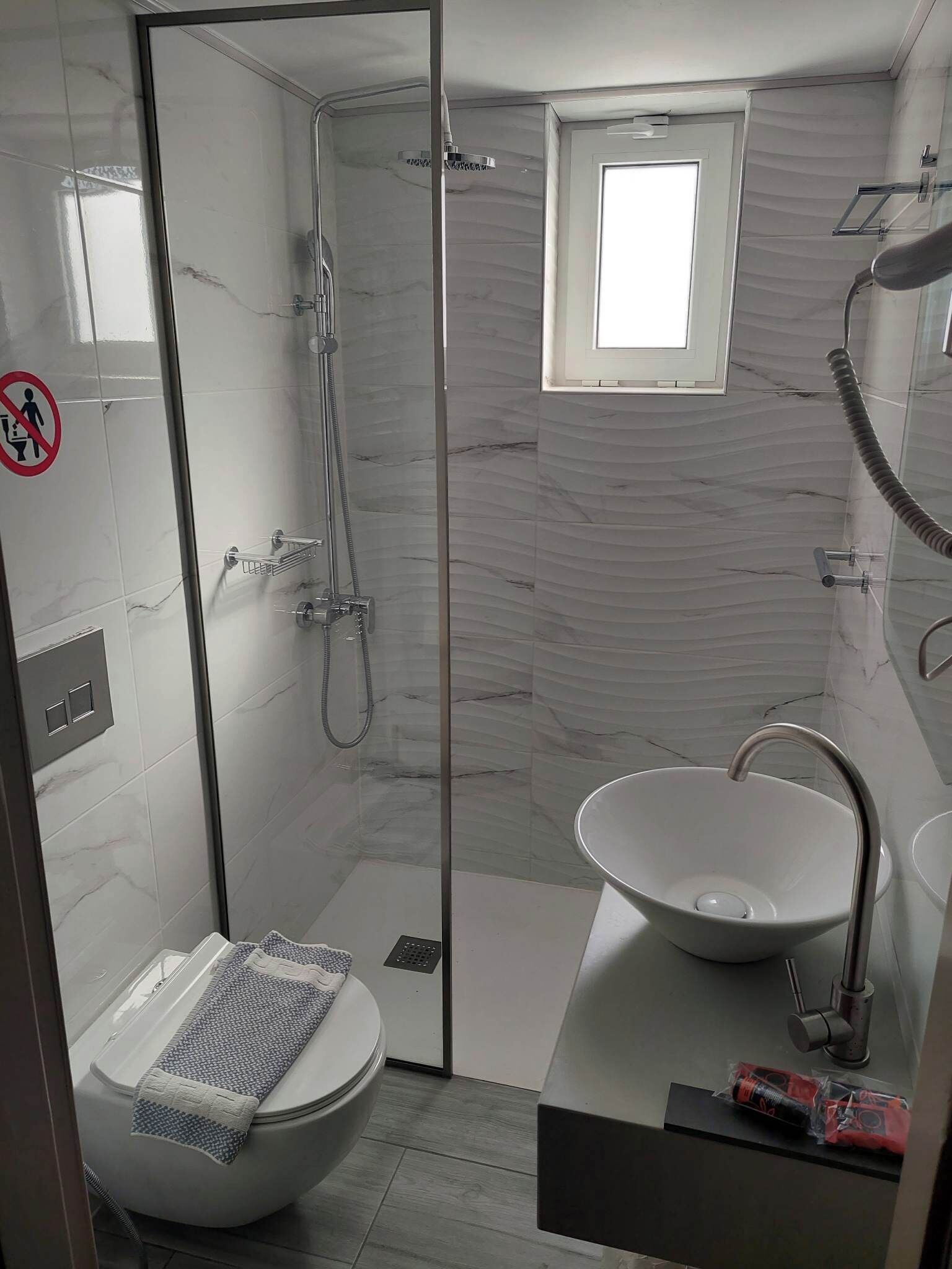Een moderne badkamer met een douchecabine, een wit wastafelmeubel en een toilet met een handdoek.