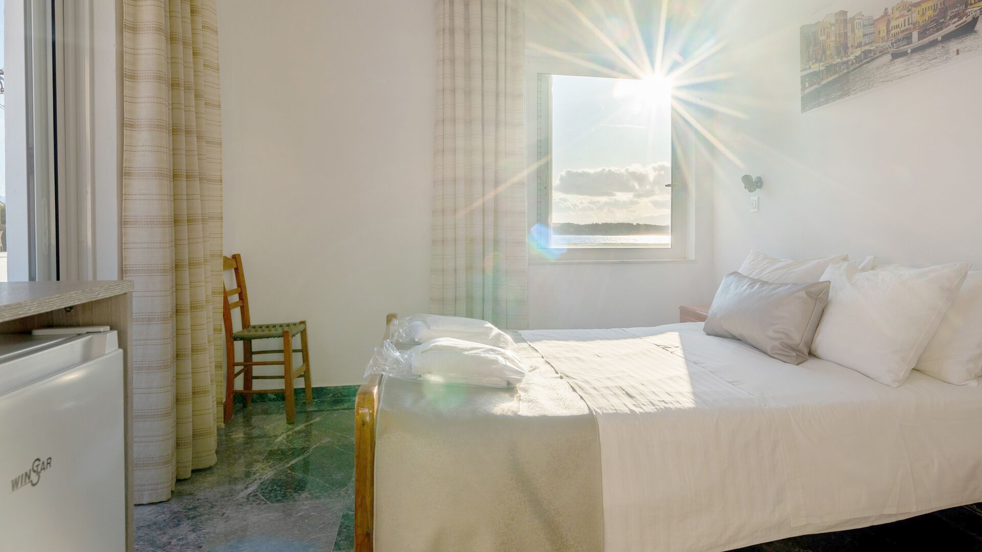 A bedroom with a bed, a chair, a window with a view, and a small table.