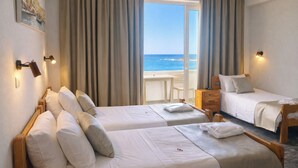 A hotel room with two beds, a desk, a chair, and a view of the sea. - Klinakis Beach Hotel (Chania)