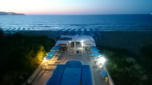 A beachside resort with a pool area, umbrellas, and lounge chairs. - Frank Apartments (Malevizi)