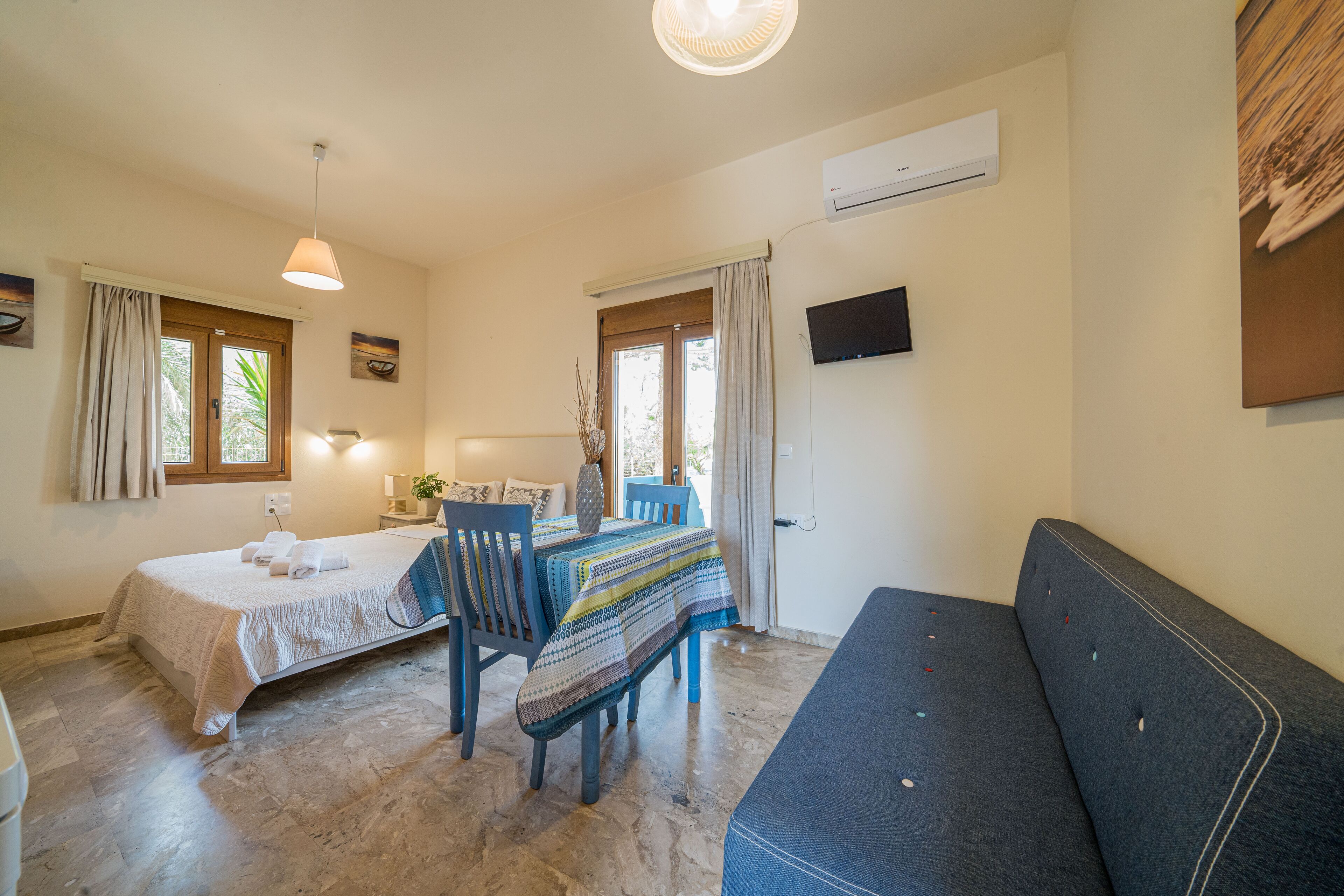 Un dormitorio con cama, sofá, mesa de comedor y televisor.