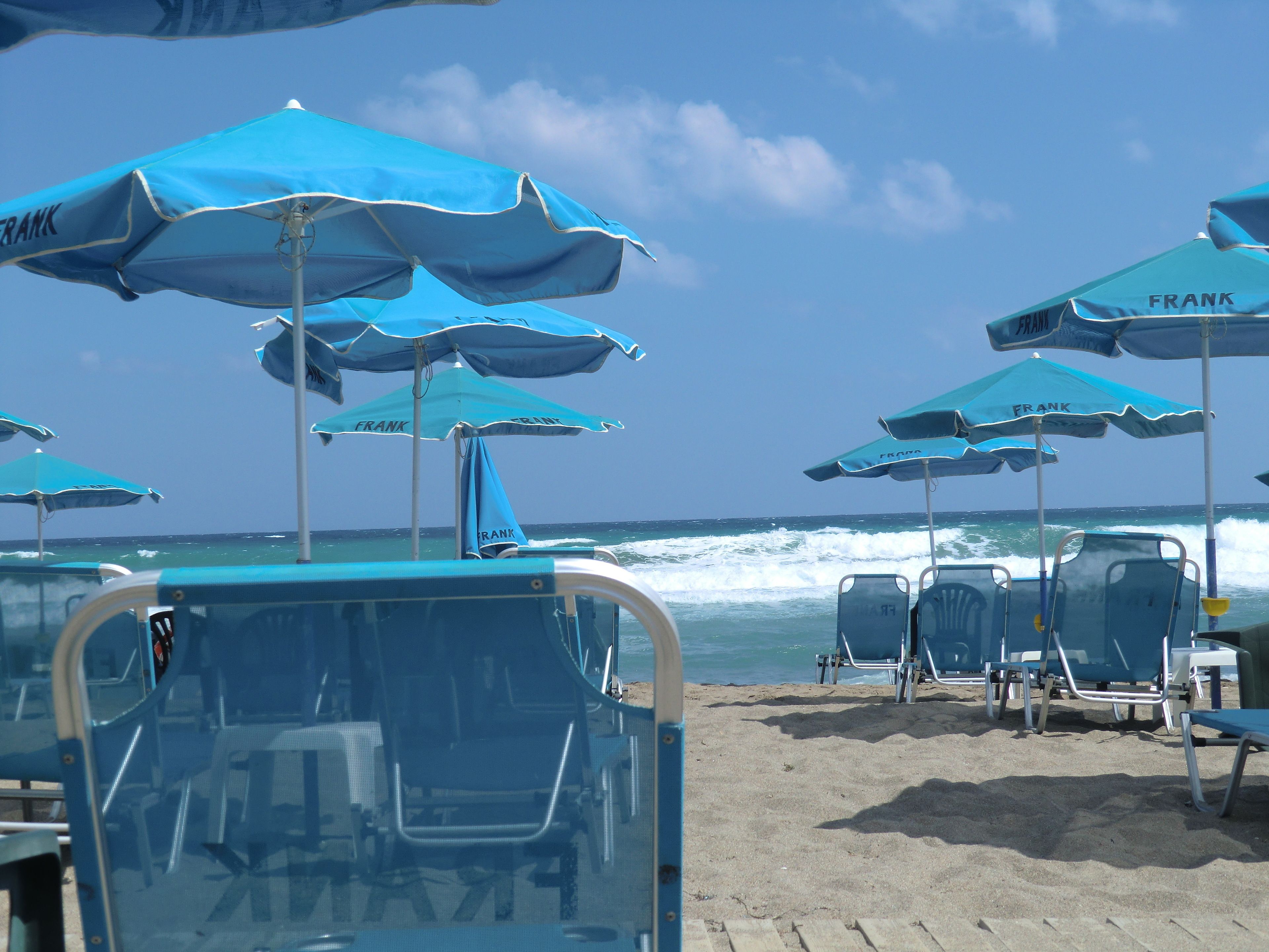 A beach with multiple blue umbrellas and lounge chairs.