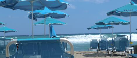 A beach with multiple blue umbrellas and lounge chairs.