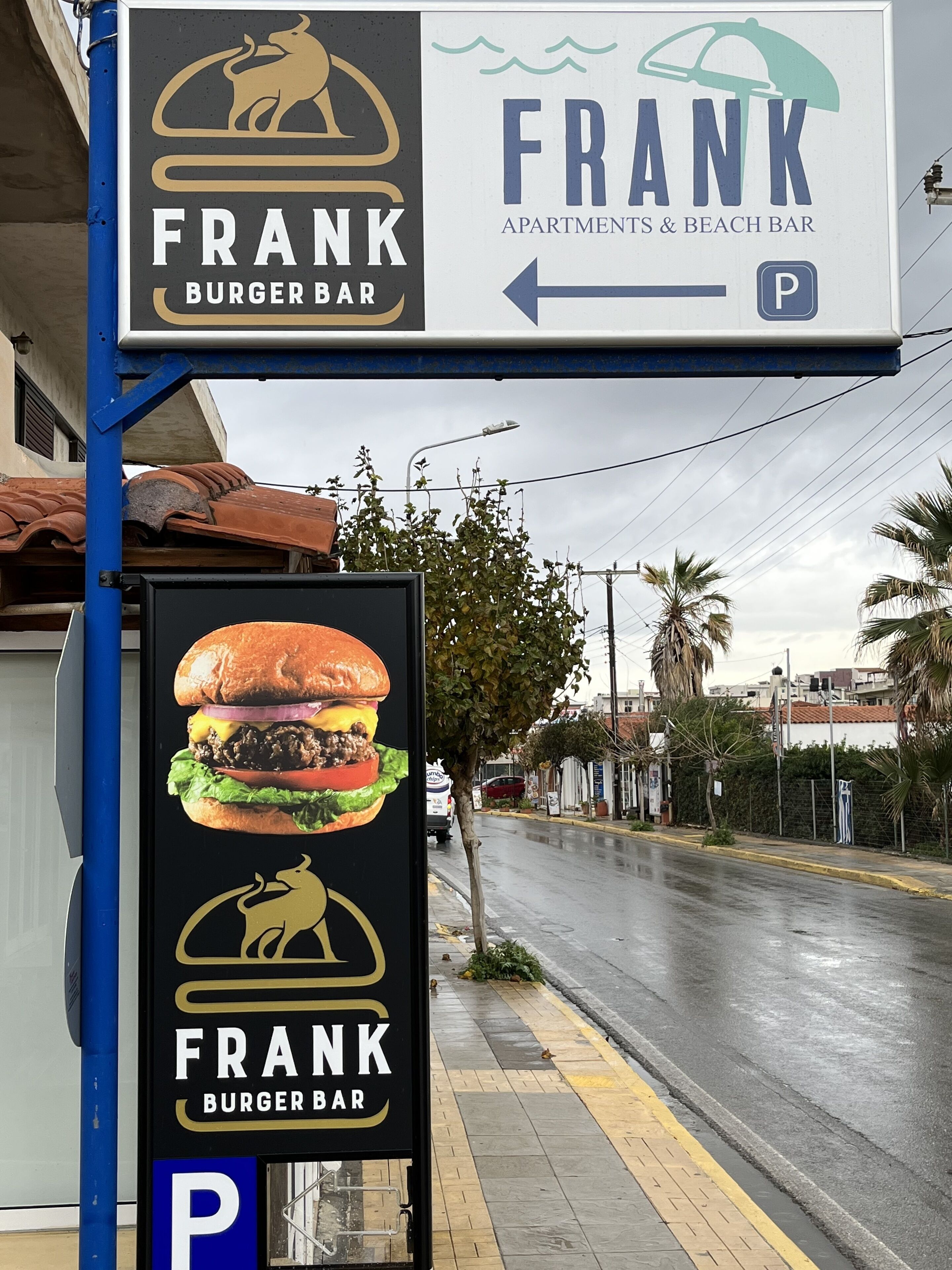 A sign for FRANK BURGER BAR with a parking symbol, indicating a nearby parking area.