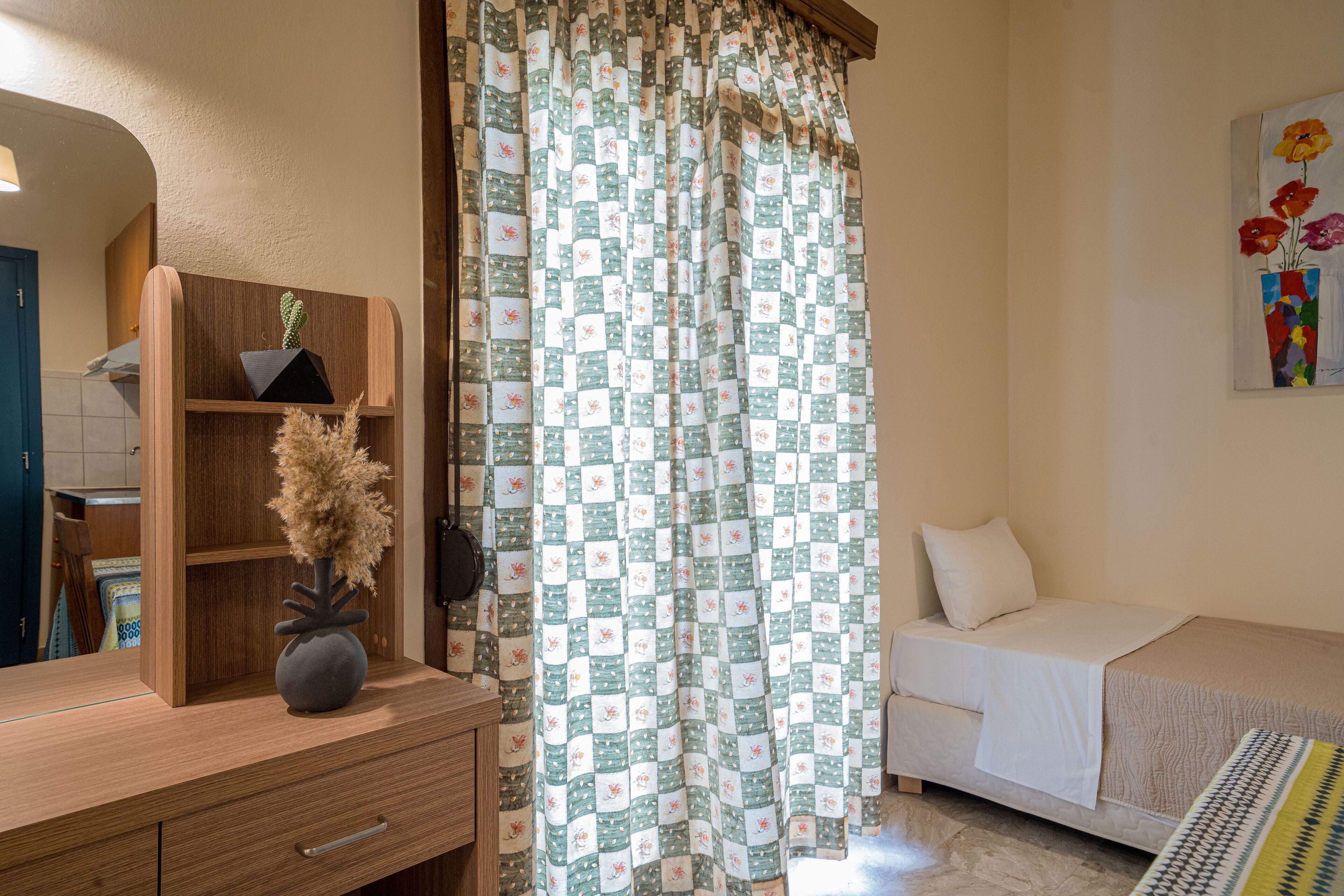 A bedroom with a bed, a nightstand, a dresser, a mirror, and a shower curtain.