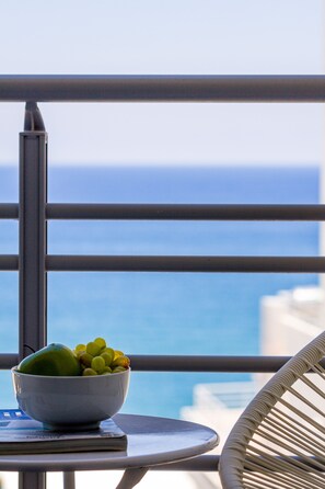 A balcony with a bowl of fruit and a chair, overlooking the ocean. - Rethymno Hills Apartments (Rethymno)