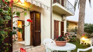 A courtyard with a white table and chairs, a potted plant, and a red flower.