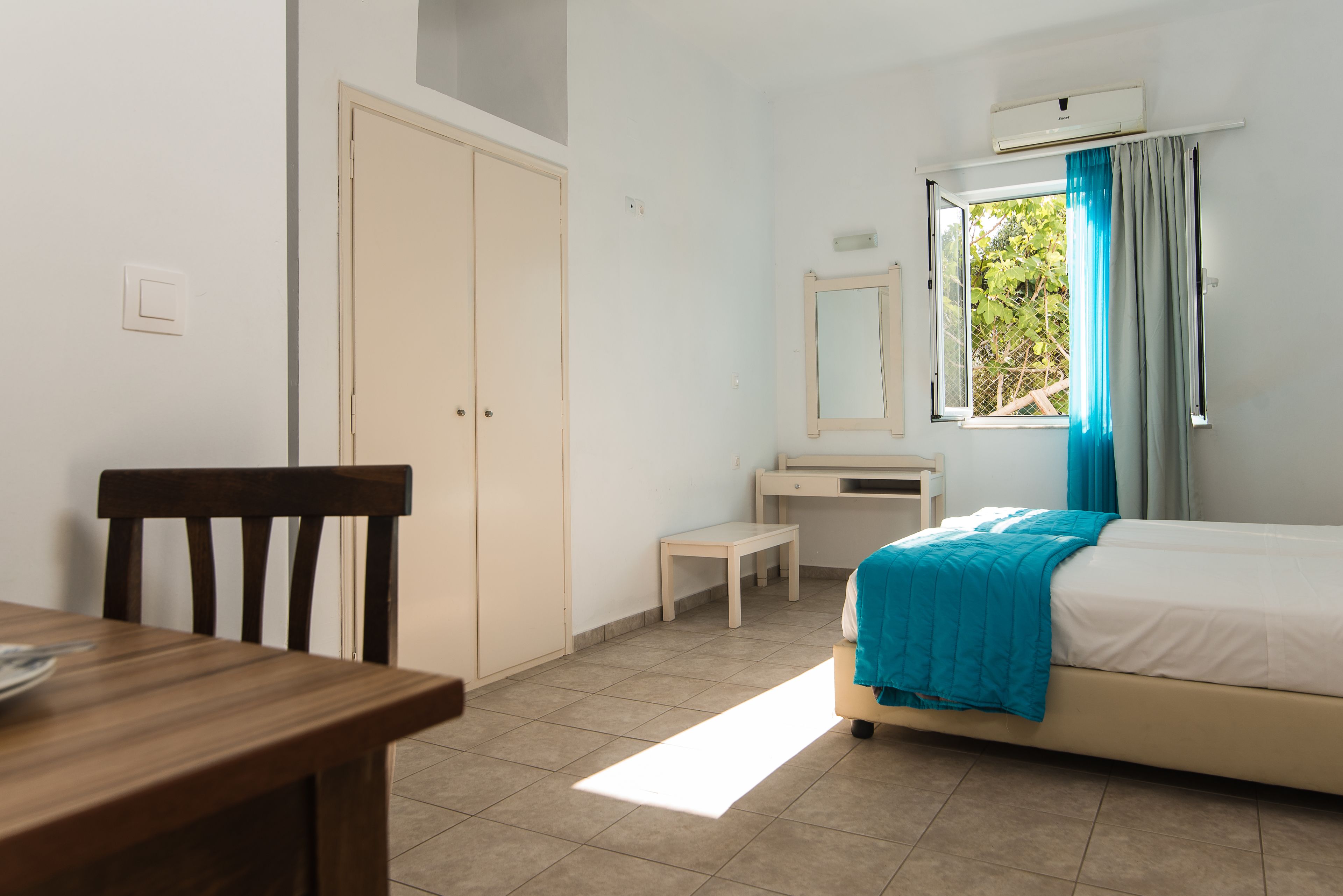 A bedroom with a bed, a desk, a chair, and a wardrobe.