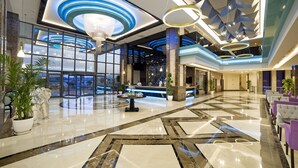 A spacious lobby with a polished marble floor, a reception desk, and modern lighting fixtures.